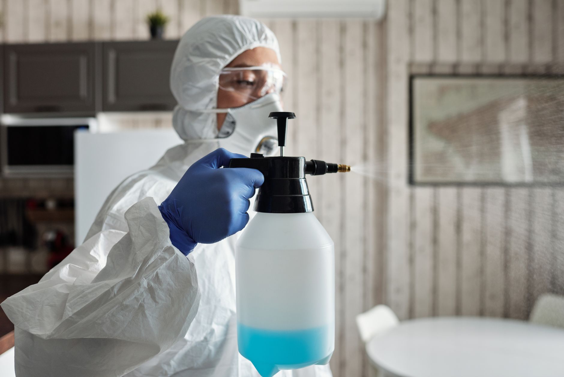 pest control technician in protective gear spraying inside a building